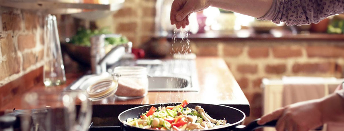 cook sprinkling salt on dish in pan on stovetop