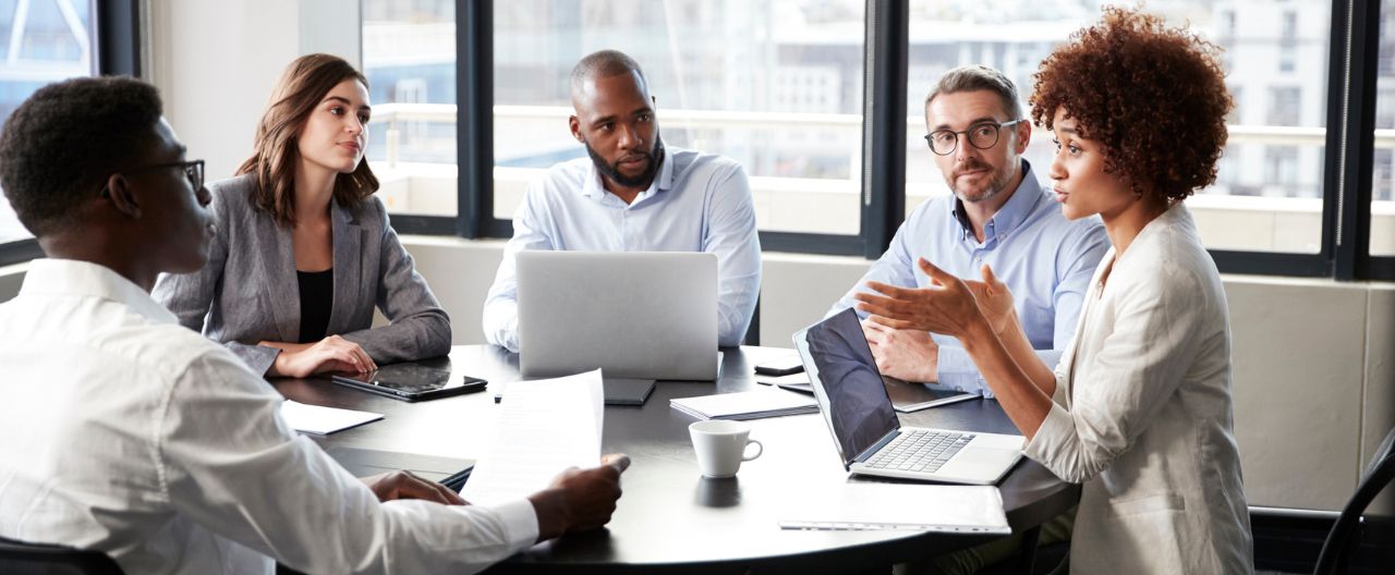 business woman leading meeting around conference table