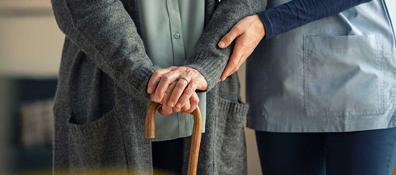 nurse assisting elderly woman with cane