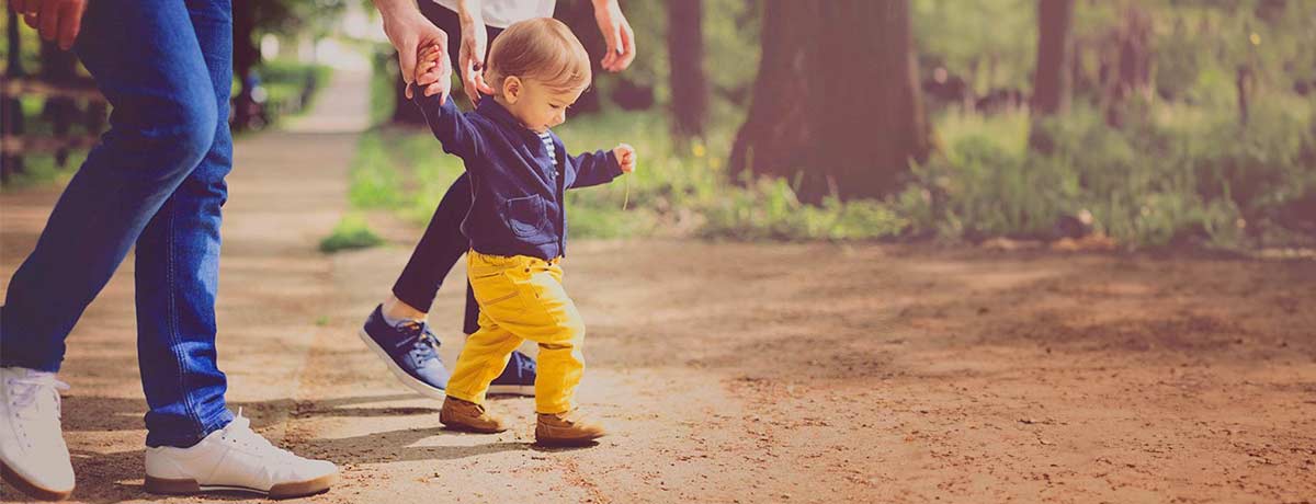 toddler walking with parents