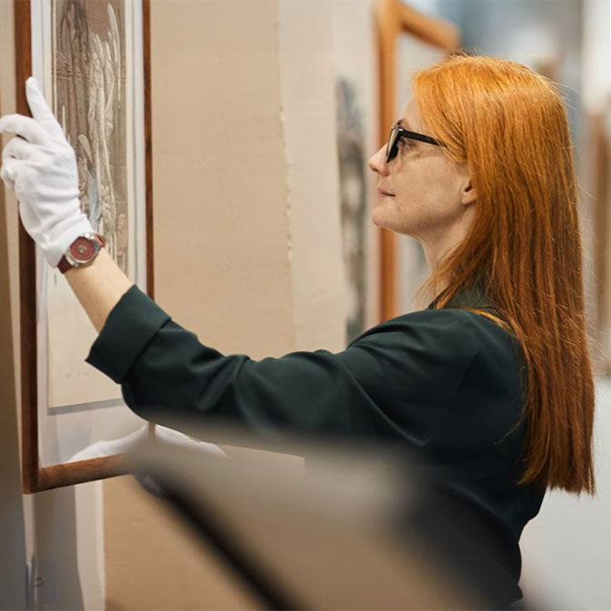 woman hangs painting in art gallery